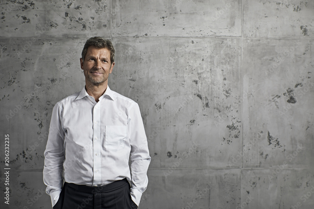 Portrait of smiling mature man in front of concrete wall Portrait of smiling mature man in front of concrete wall