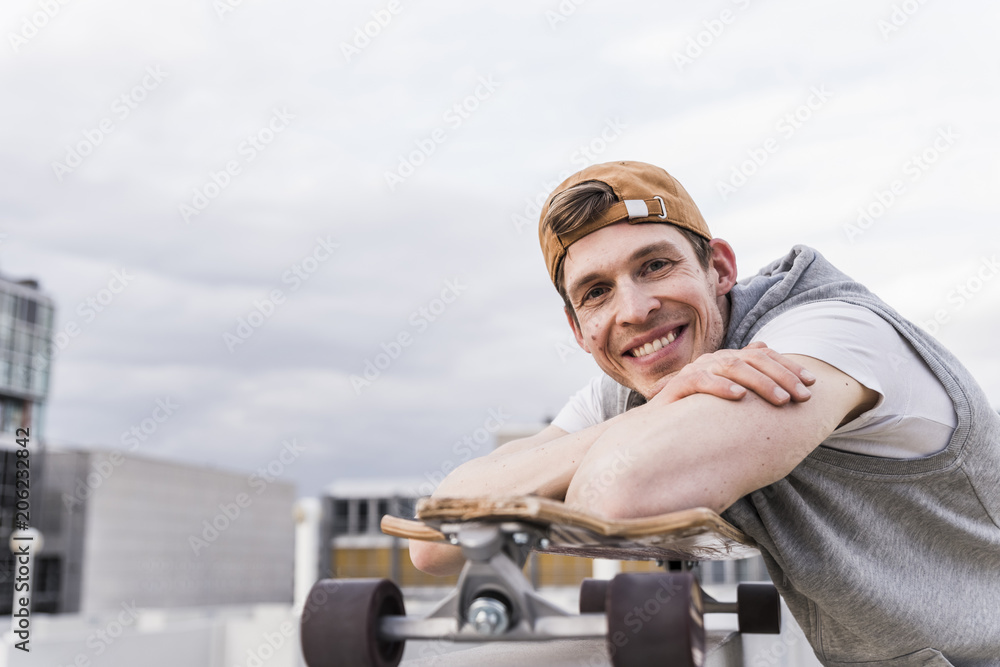 Portrait of smiling man with skateboard leaning on a wall Portrait of smiling man with skateboard leaning on a wall