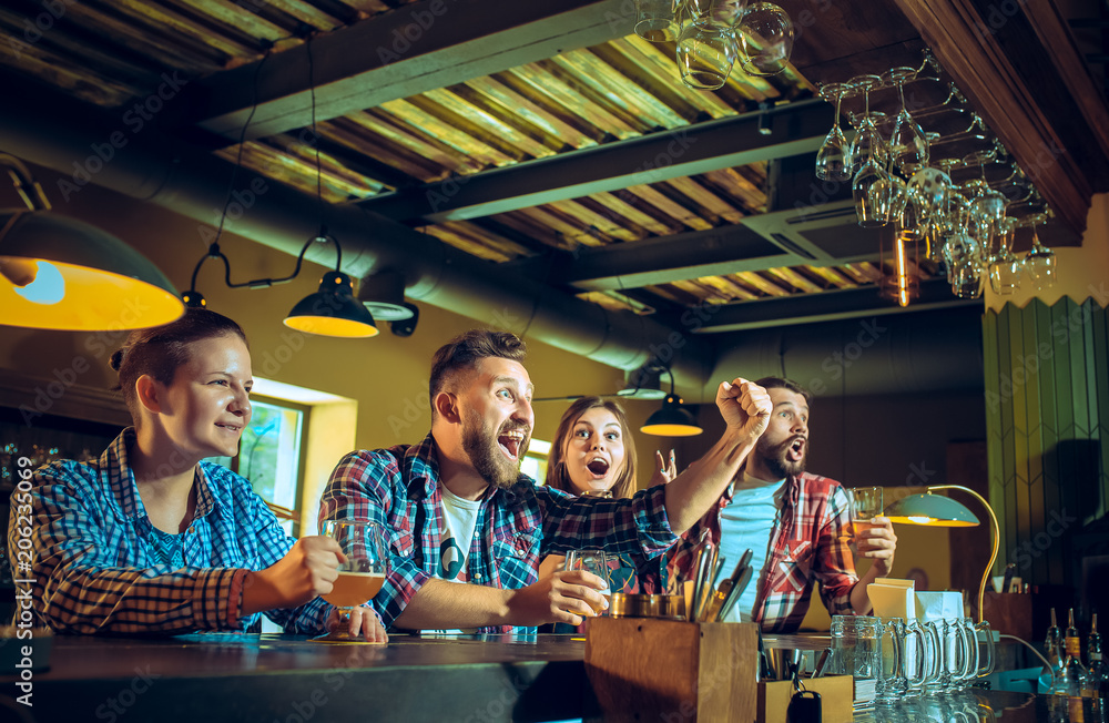 Sport, people, leisure, friendship and entertainment concept - happy football fans or male friends drinking beer and celebrating victory at bar or pub Sport, people, leisure, friendship and entertainment concept - happy football fans or male friends drinking beer and celebrating victory at bar or pub