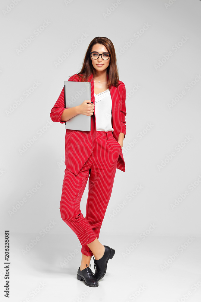 Fashion portrait of a young beautiful woman in business style. Red pantsuit, glasses. Fashion portrait of a young beautiful woman in business style. Red pantsuit, glasses.