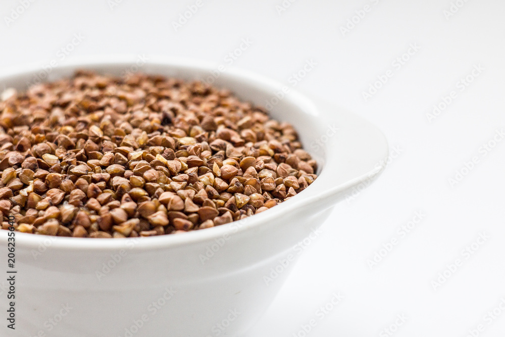 buckwheat groats in a white bowl on a white background close up buckwheat groats in a white bowl on a white background close up