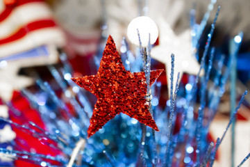 Festive holiday background with blurred flag in background and glitter star and decorative bokeh elements in foreground - red white and blue