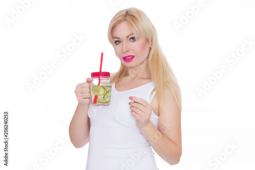 A friendly blond woman holds a glass of water and lime in her hands. A girl is drinking lemonade. Concept - healthy food, thirst quenching in summer