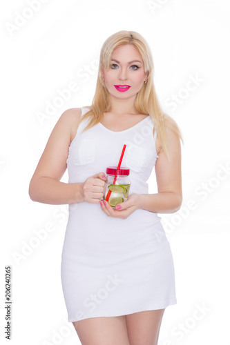 A friendly blond woman holds a glass of water and lime in her hands. A girl is drinking lemonade. Concept - healthy food  thirst quenching in summer