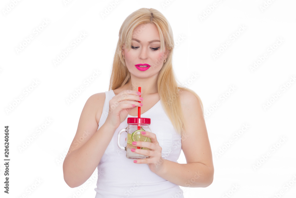 A friendly blond woman holds a glass of water and lime in her hands. A girl is drinking lemonade. Concept - healthy food, thirst quenching in summer A friendly blond woman holds a glass of water and lime in her hands. A girl is drinking lemonade. Concept - healthy food, thirst quenching in summer