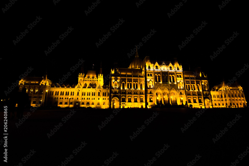 Night Budapest Parliament in yellow lights. Dark sky and architecture background. European city travelling lifestyle photo.