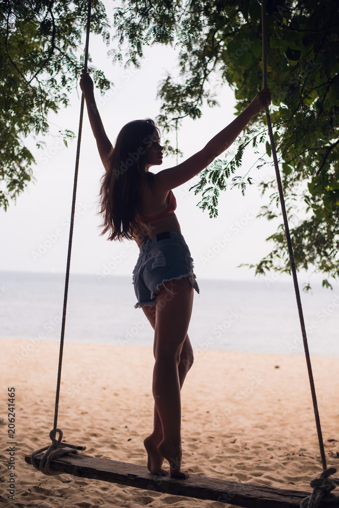beautiful girl in a hat standing on the hanging swing on the sea on the  beach of Thailand Stock Photo | Adobe Stock