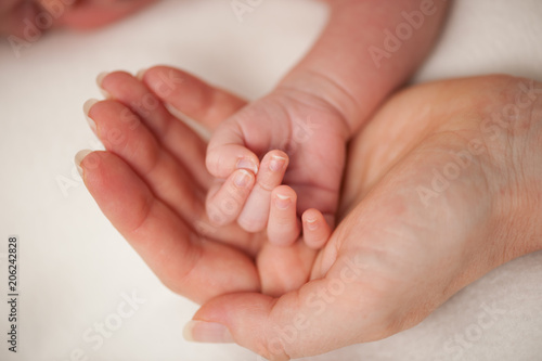 Mama holds new born hand in her hand