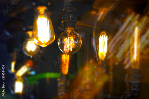 Vintage glowing light bulb lamp hanging. Interior decoration in old style luxury design. Focus on the foreground light.