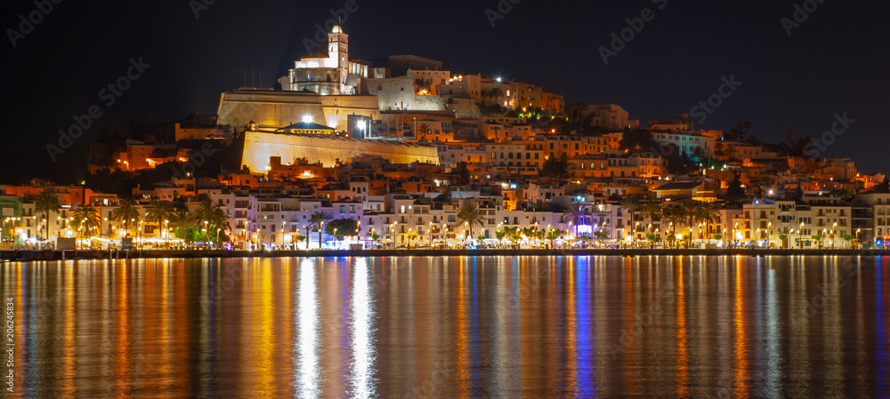 Ibiza town and castle seen at night reflected across the water,