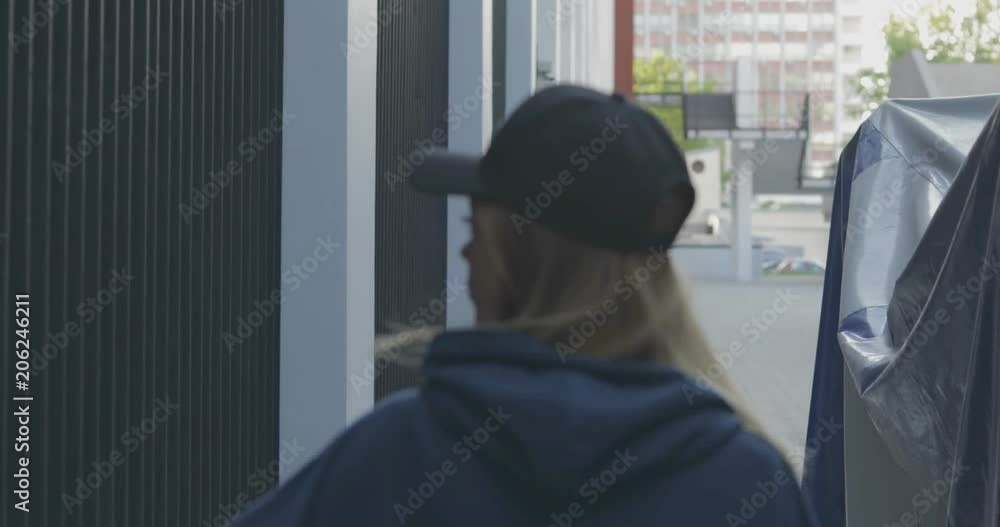 Back view of trendy girl wearing cap and blue sweatshirt walks down alley.. City urban style. 4K video shooting by handheld gimbal Back view of trendy girl wearing cap and blue sweatshirt walks down alley.. City urban style. 4K video shooting by handheld gimbal