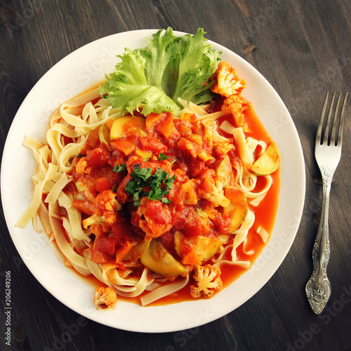 Ribbon pasta with Arrabiata sauce. Close up. Mediterranean dish. Tagliolini pasta with vegetables. Cauliflower, courgette and tomato stew. Italian cuisine. Vegan and vegetarian. Top view. Toned photo.