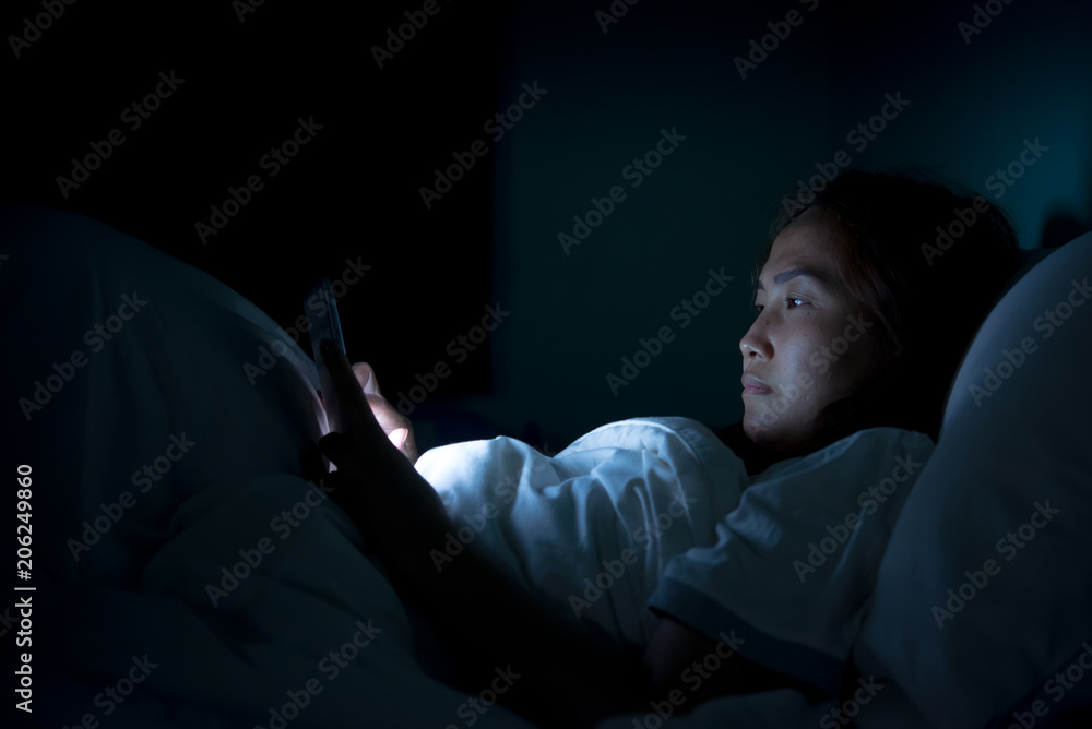 Asian woman play smartphone in the bed at night,Thailand people Asian woman play smartphone in the bed at night,Thailand people