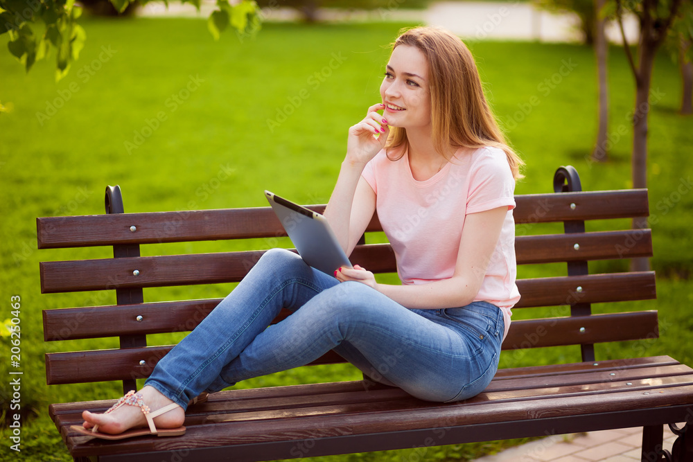Fototapeta premium Pensive girl with tablet sitting on the bench