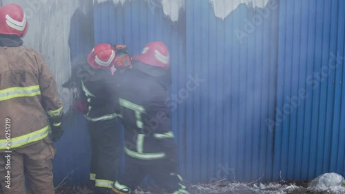 Market with carpets is on fire. Fireman gworking with chainsaw and the axe photo