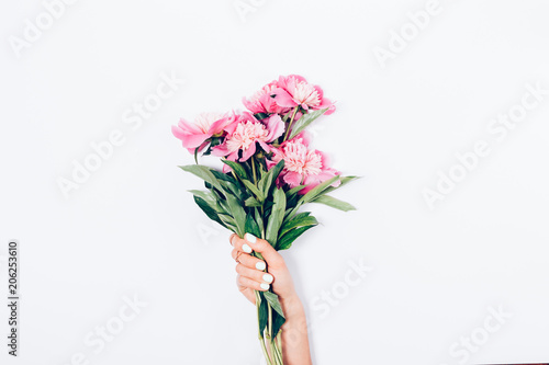 Women's hand with trendy manicure holding bouquet of pink peonies