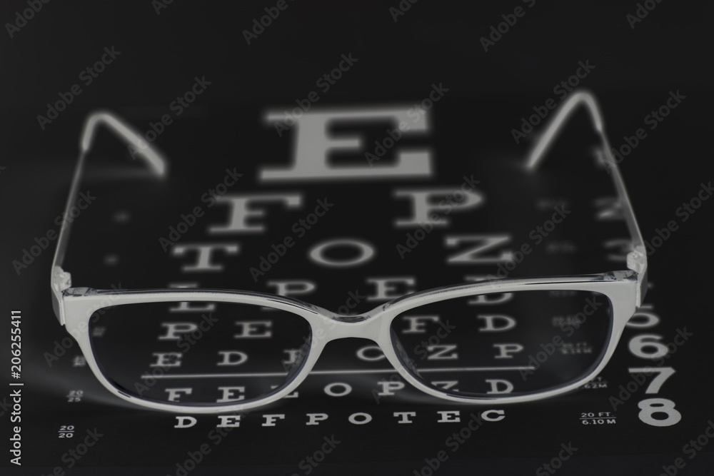 Fototapeta premium Eyeglasses on eyesight test chart background.