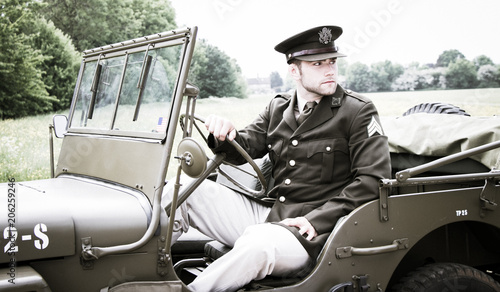 Handsome American WWII GI Army officer in uniform riding Willy Jeep