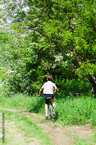 The boy is riding a bicycle along the village road.