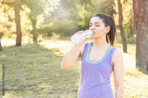 Young woman drinking water after workout, feeling good. Active lifestyle.