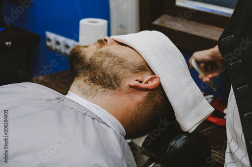 The barber shears the beard and mustache of a man with a hipster. © sergo321