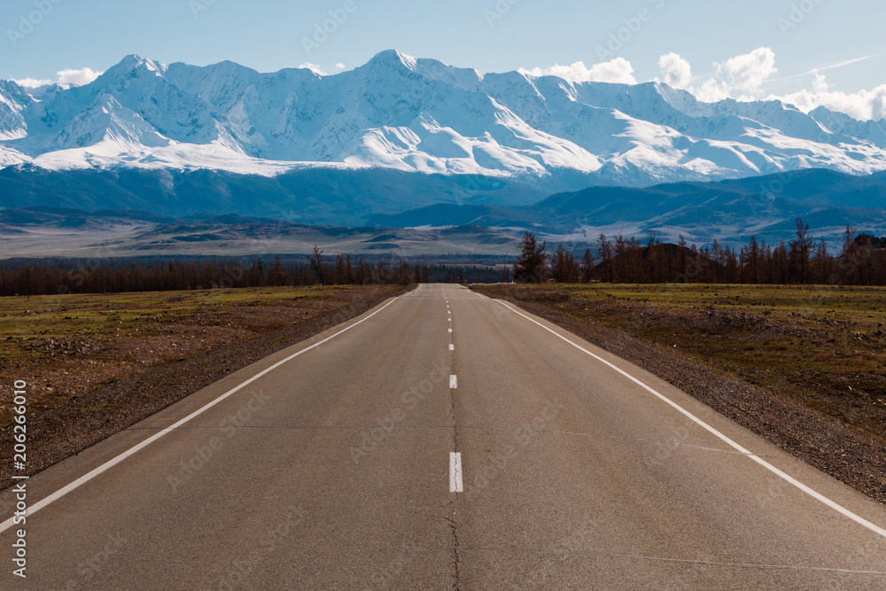 empty highway leading to the mountains with snow caps. Altai mountains landscape empty highway leading to the mountains with snow caps. Altai mountains landscape