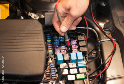 Technicain checking car fuse by lamp tester which nagative pole of lamp tester connected with car frame and positive pole measure at secondary of fuse box.