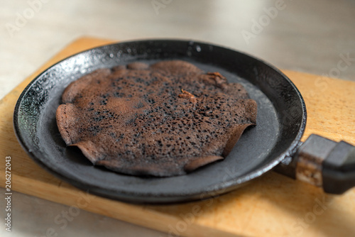 Scorched pancake in a frying pan and wooden stand