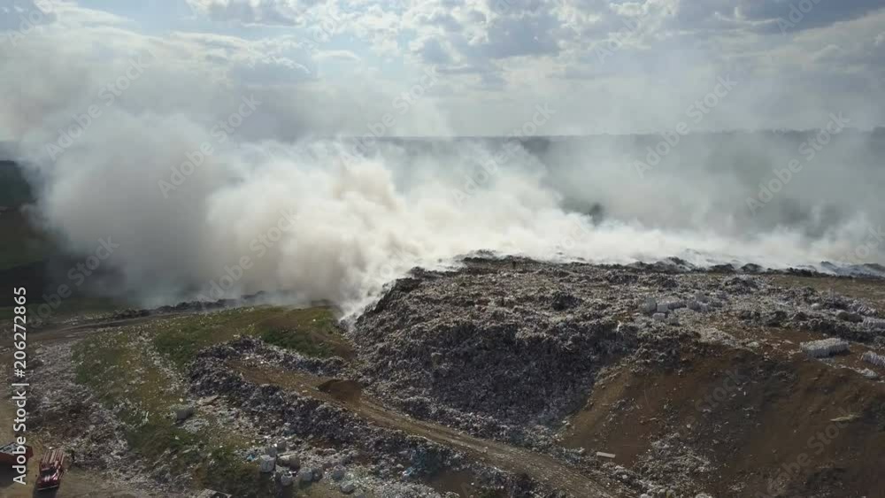 Garbage dump pollutes the environment. Strong wind rises toxic smoke of burning garbage into the air.