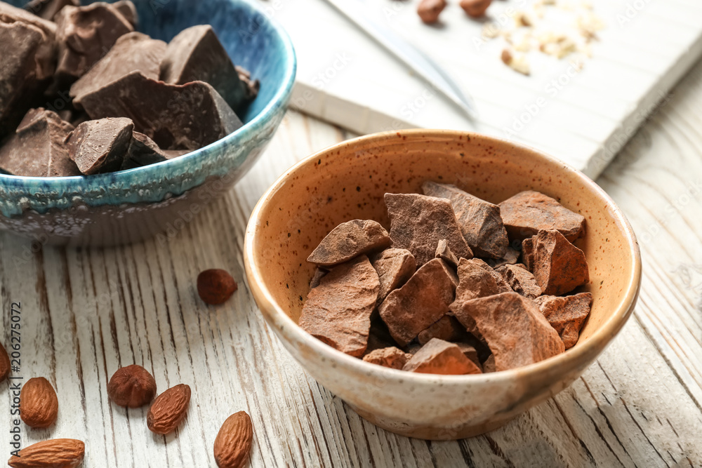 Bowl with pieces of delicious dark chocolate on wooden table Bowl with pieces of delicious dark chocolate on wooden table