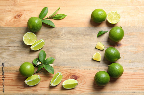 Frame of fresh ripe limes on wooden background, top view