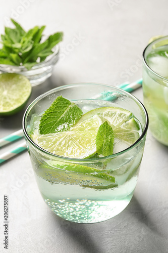 Refreshing beverage with mint and lime in glass on table