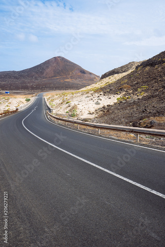 Desolates straight road over a surreal landscape with majestic volcano creater in the distance. Sao Vicente Cape Verde