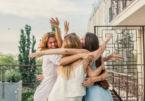 Girls Party. Beautiful Women Friendship on the balcony or roof At Bachelorette Party during sunset. They are hugging photo