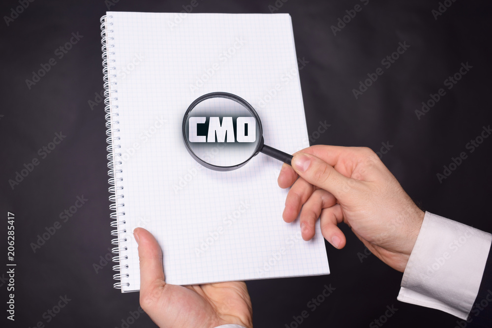Businessman looking at a magnifying glass word:CMO Businessman looking at a magnifying glass word:CMO