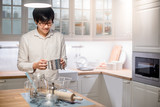 Young Asian happy man standing in front of counter in kitchen preparing cooking wares for meal
