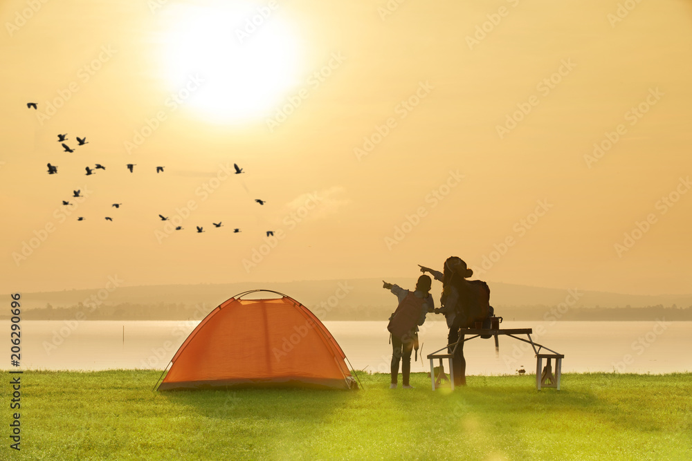 Φωτογραφία mother and daughter camping near the lake with sunset or sunrise background,happ