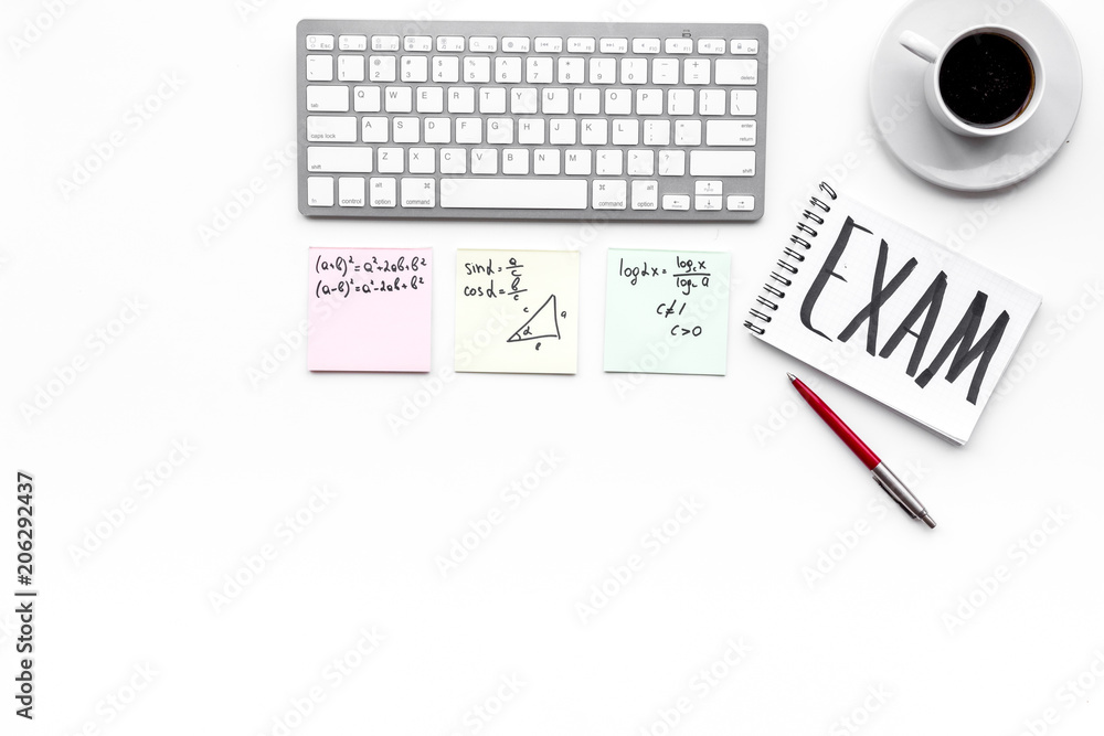 Exam concept. Lettering Exam in notebook on student's work desk on white backgrond top view copy space Exam concept. Lettering Exam in notebook on student's work desk on white backgrond top view copy space
