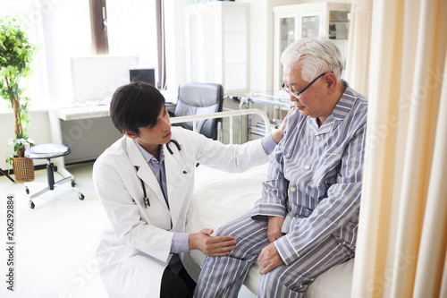 医療用ベッドで医師の診断を受ける高齢者の男性。