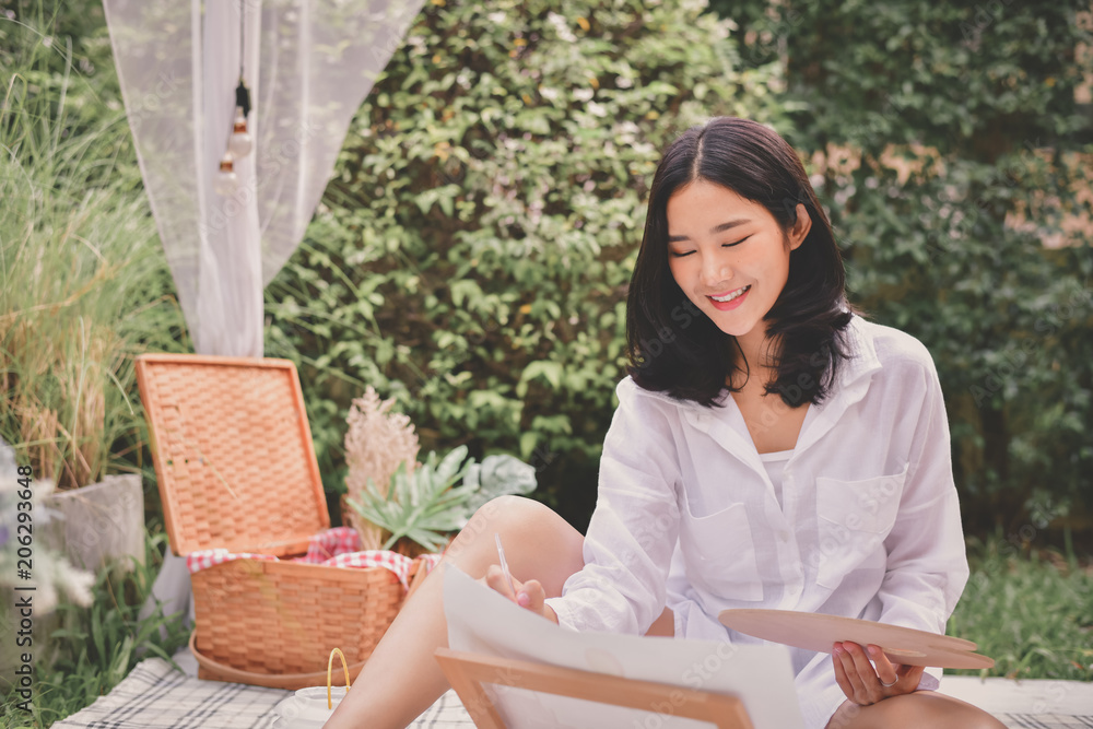 Obraz premium Concept Artist Beautiful girl. Beautiful women are creating art. Beautiful woman is painting happily. Young artist painting outside the house.