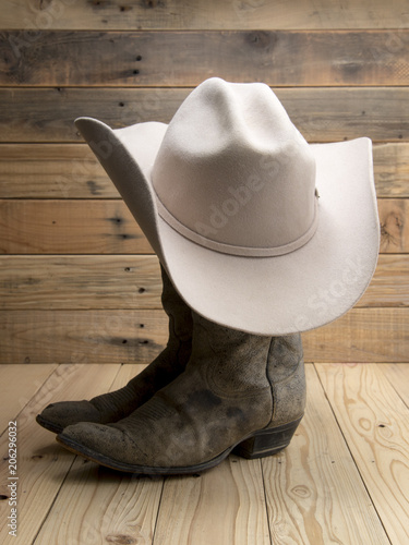 Cowboy boot and western hat on wooden background.