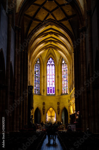 Two unidentified people walking along aisle in dark church. Kaysersberg  Alsace.