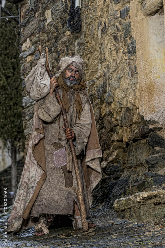 Man, dressed in rags, begging through the streets of a village Man, dressed in rags, begging through the streets of a village