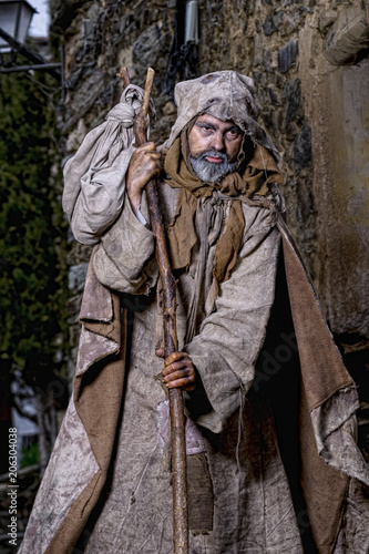 Man, dressed in rags, begging through the streets of a village