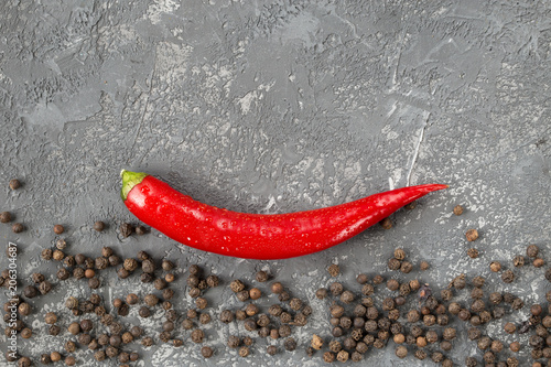 Chili pepper and peppercorns on stone background