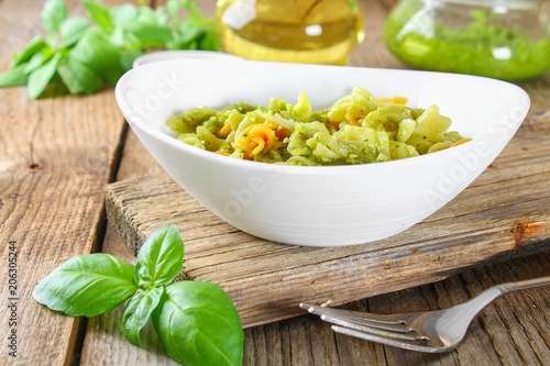 Pasta with pesto sauce on an old wooden table.