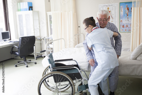 介護士が、リハビリ中の老人を車椅子に座らせている。