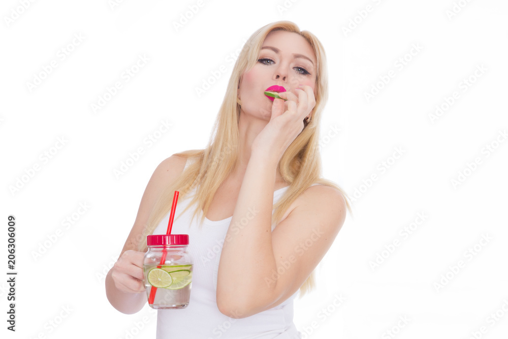 A woman on a white background holds a glass with lemonade in one hand, and in the second hand holds a piece of lime A woman on a white background holds a glass with lemonade in one hand, and in the second hand holds a piece of lime