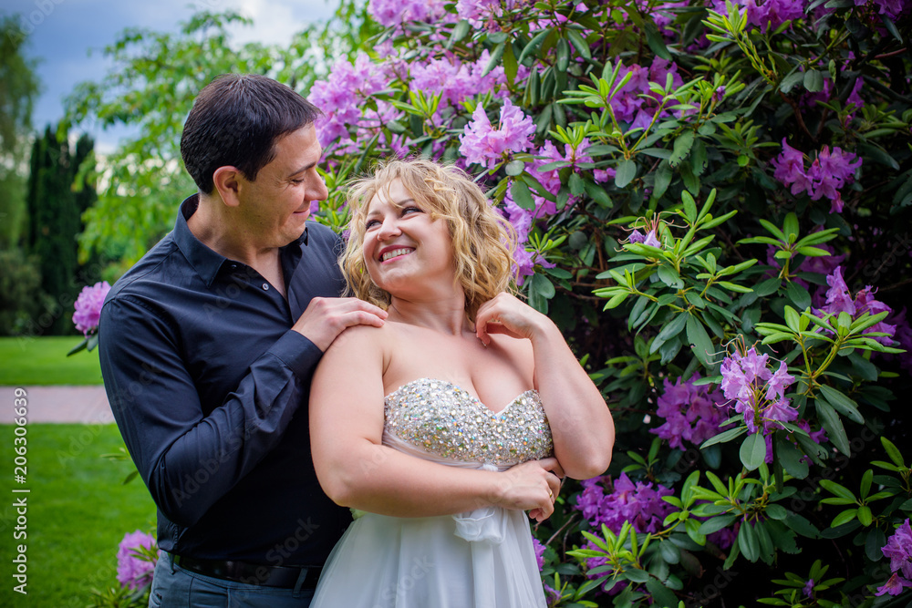 Romantic tenderness bride and groom at park. Young lady plus size enjoying moments in summer time. Beautiful bride posing with groom in her wedding day, pretty girl in a wedding dress Romantic tenderness bride and groom at park. Young lady plus size enjoying moments in summer time. Beautiful bride posing with groom in her wedding day, pretty girl in a wedding dress