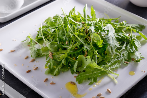 Eruca vesicaria fresh green lettuce dietary on white beautiful tableware.